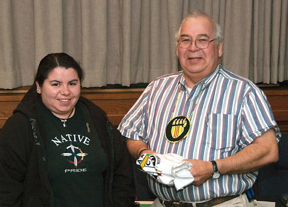 Rose Alloway (L), student President of Native American Student Movement (NASM) presented a NASM  T-shirt to Alan Caldwell. Caldwell, a Vietnam era veteran and Principal of Indian Community School,  presented a detailed talk and open discussion on the hist