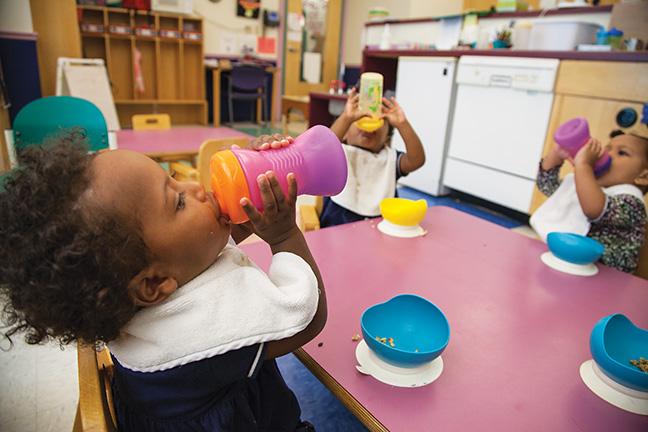 Skai, Sanai, and Myat (left to right) refresh themselves with a quick swig of juice after a long morning of play in the 11-15 months room at MATC’s Child Care Center.