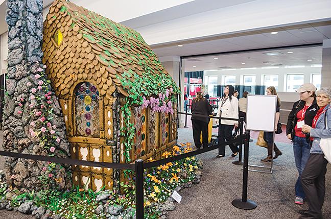Attendees of the Midwest Foodservice Expo gaze at the massive gingerbread house on display.