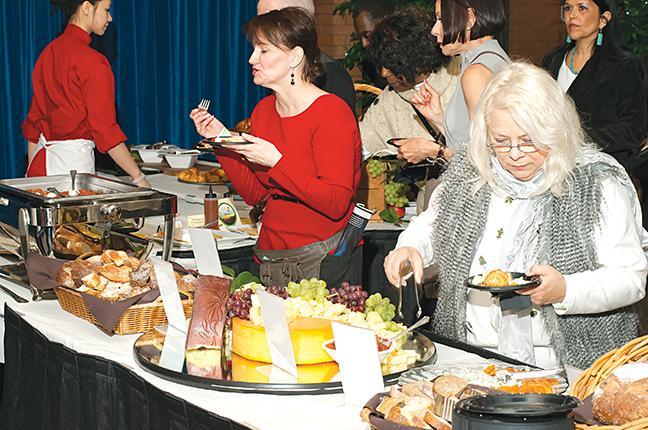 With a plate full of food, a woman in line samples some of the gourmet cheese.