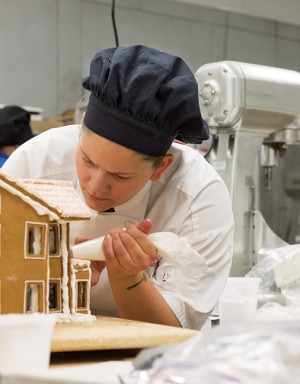 Lauretta Archibald, Baking and Pastry Arts program, pipes icing onto her gingerbread house for the annual gingerbread house competition.