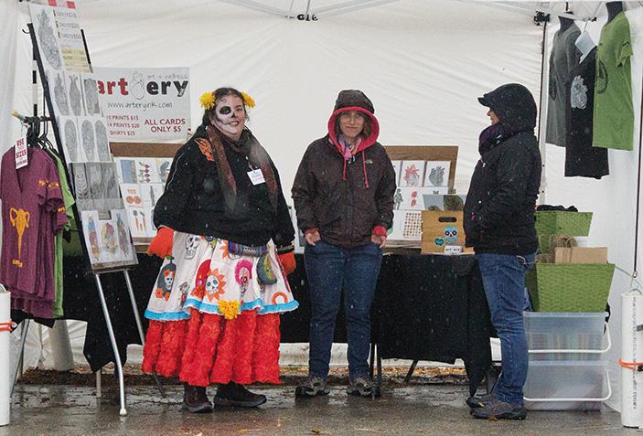 Founder of the “Dia de los Muertos,” Jessicanne Celeste Contreras Skierski, and friends take cover from the rain.