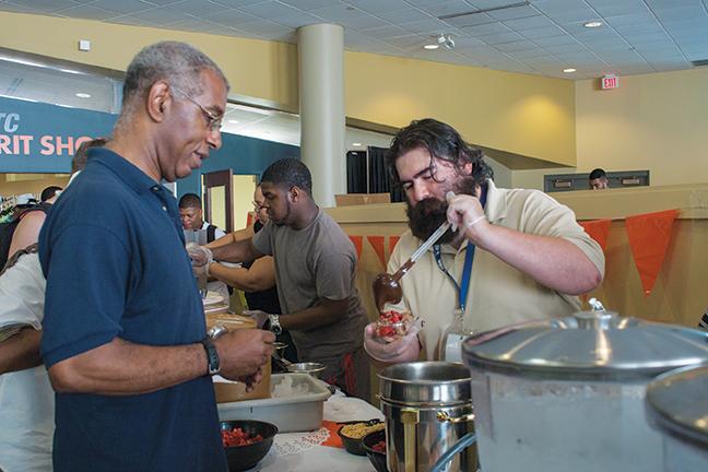 Michael Fisher, Sergeant at Arms of the Student Government, was pleased to pour hot fudge onto the students bowl of ice cream, while Reggie Adams, Vice President of the Student Government, served the ice cream. 