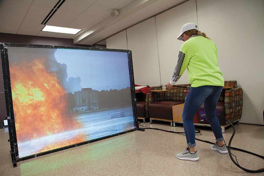 Steffanie Peterson, first-year nursing student, “fights” the virtual fire and successfully extinguishes it at the Mequon campus Safety Fair.