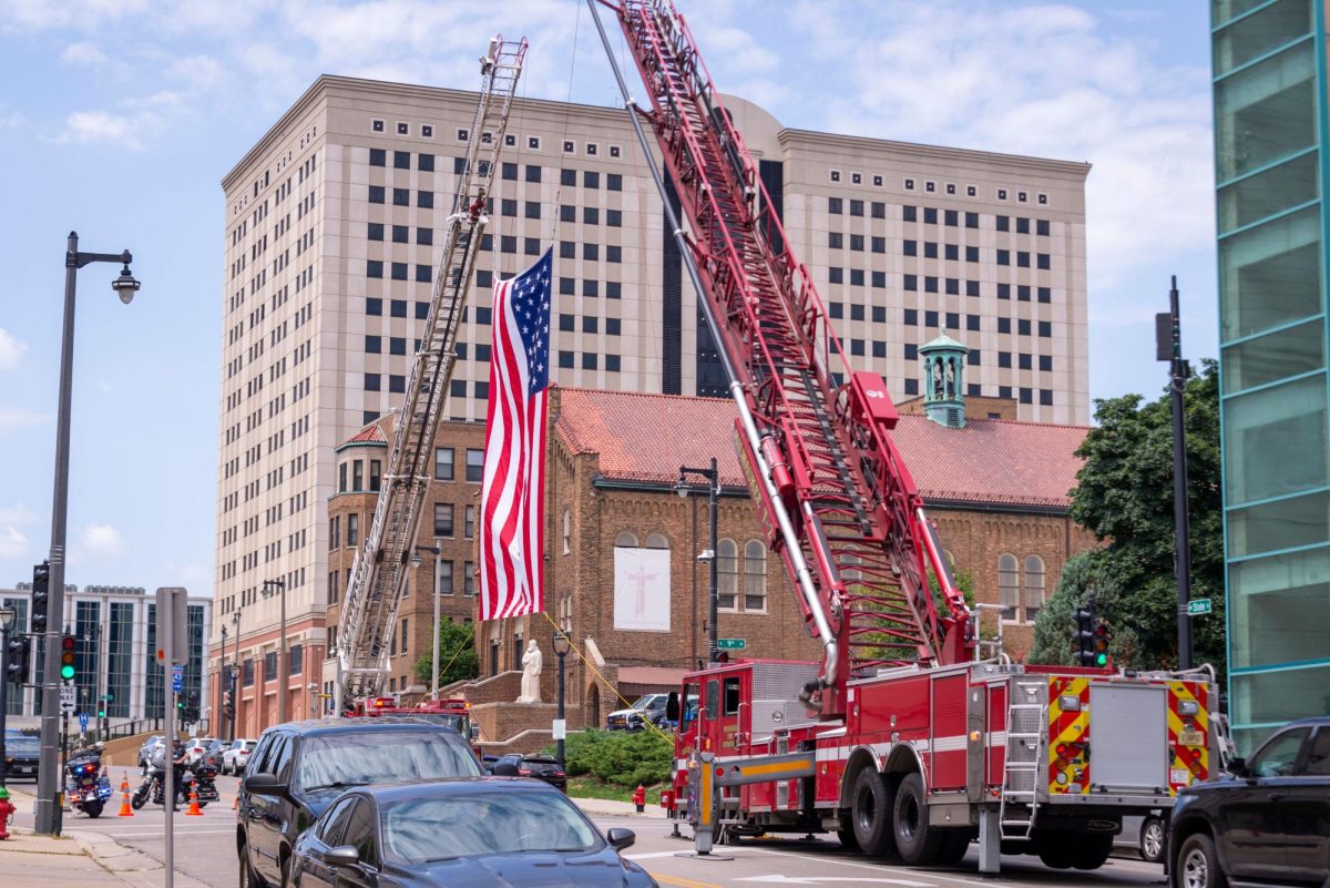 The American flag is being raised by the downtown Milwaukee Fire Department.