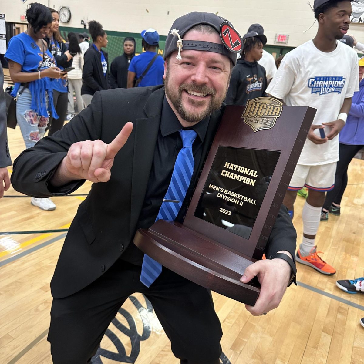 Assistant Athletic Director Travis Mrozek is all smiles holding a NJCAA Region 4 Championship trophy.