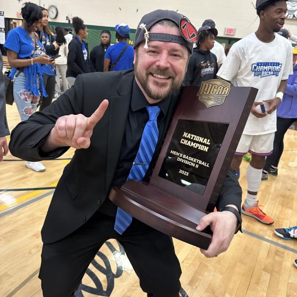 Assistant Athletic Director Travis Mrozek is all smiles holding a NJCAA Region 4 Championship trophy.