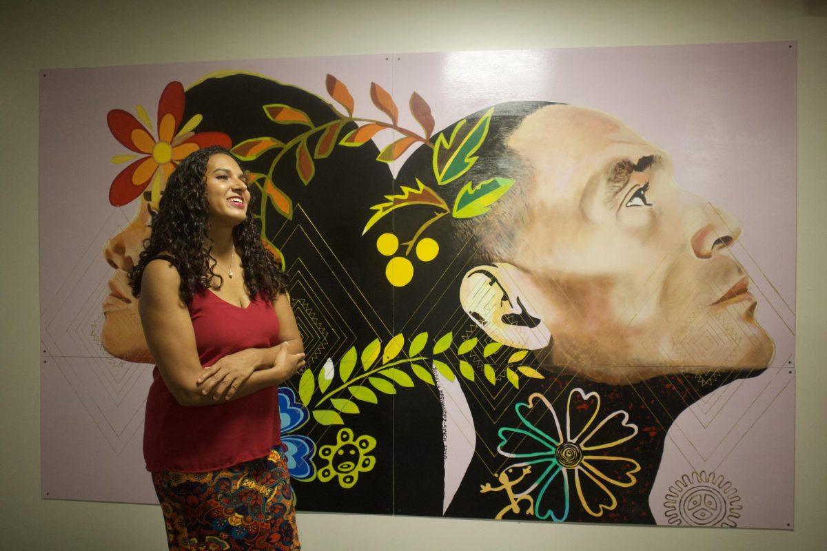 Rozalia Hernandez Singh poses with her art in the Cyber Cafe at MATC's Education Center at Walker's Square. On her Instagram, Singh describes herself as a  muralist, caricaturist, painter, art teacher and graphic illustrator.