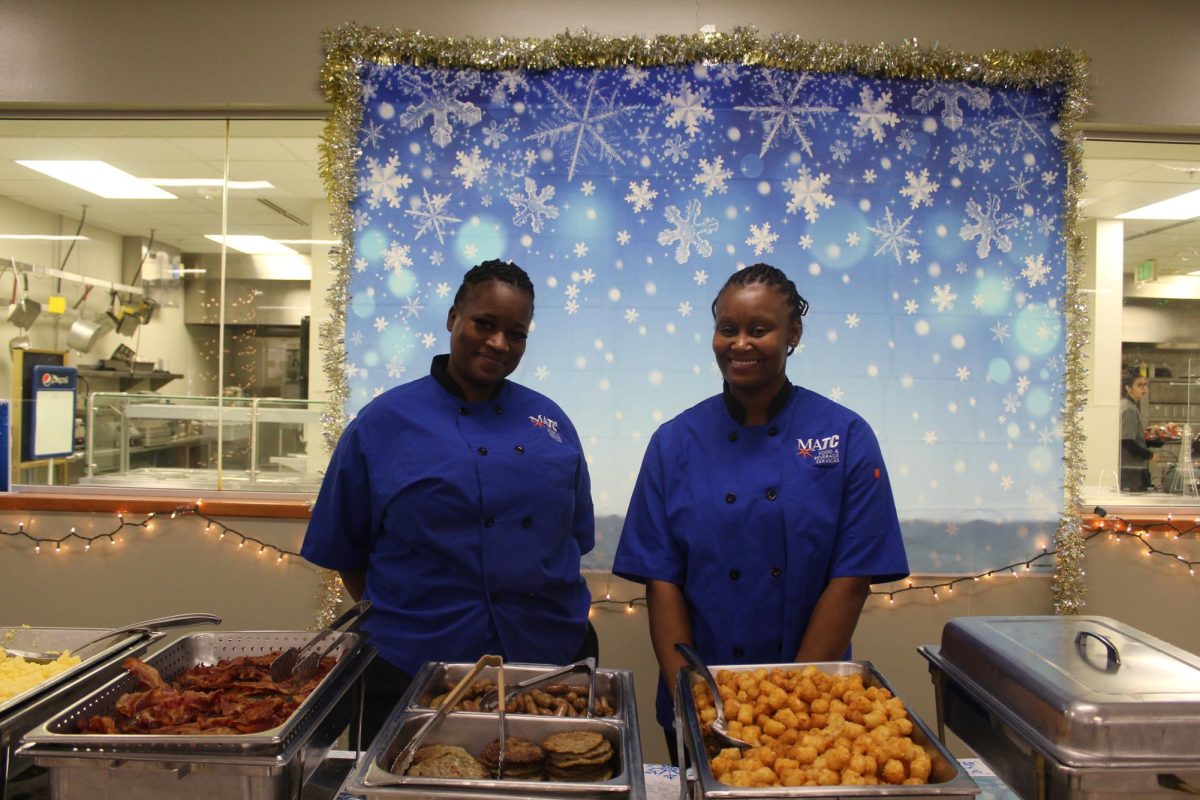 Two MATC Food & Beverage Services workers pose in front of the food they served at the family-friendly, Snowman Spectacular event at the Oak Creek campus.