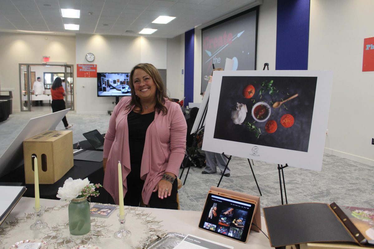 Photography student Laura Starks next to her display for the Create the Spark portfolio night, May 8 2025.