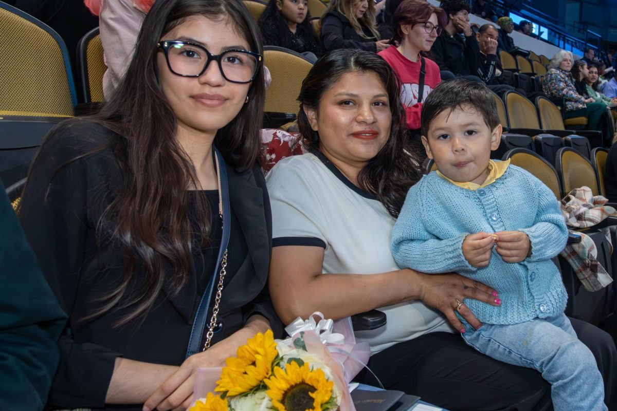 Family members sit in the stands at Panther Arena holding flowers for an MATC graduate.