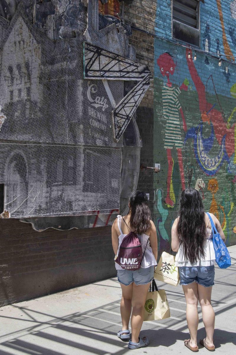 Two visitors look at the "Catz Beer" mural by Brandon Minga located at Black Cat Alley.