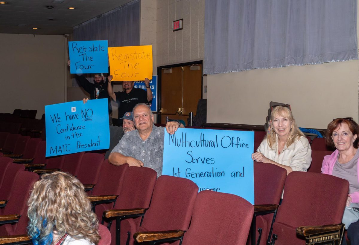 During an MATC District Board meeting, members of the MATC community hold signs in silent protest of the elimination of the Multicultural Services office and in support of the four staff members who were terminated.