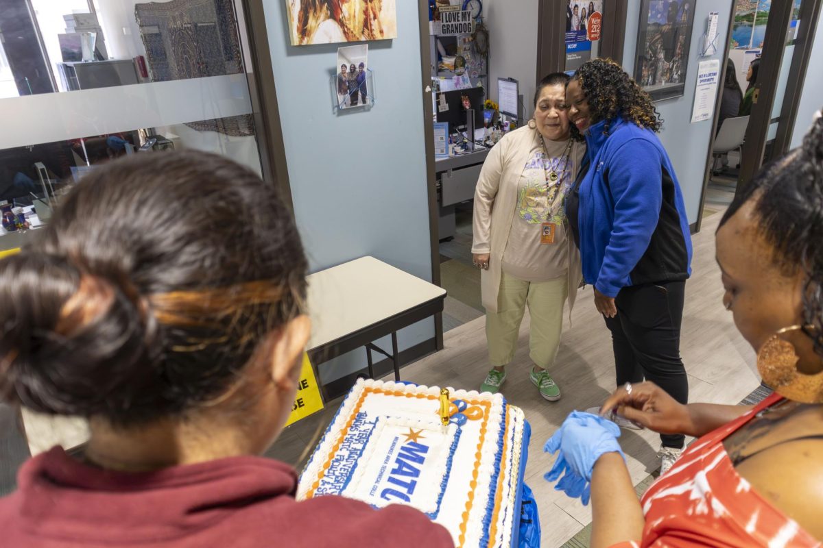Tanya Torres of the Multicultural Services office (L) receives a hug from Lead Child Care Teacher, Tamara Allen (R) and cake as a thank you for spreading awareness of Little Stormers Village on July 31, 2025.