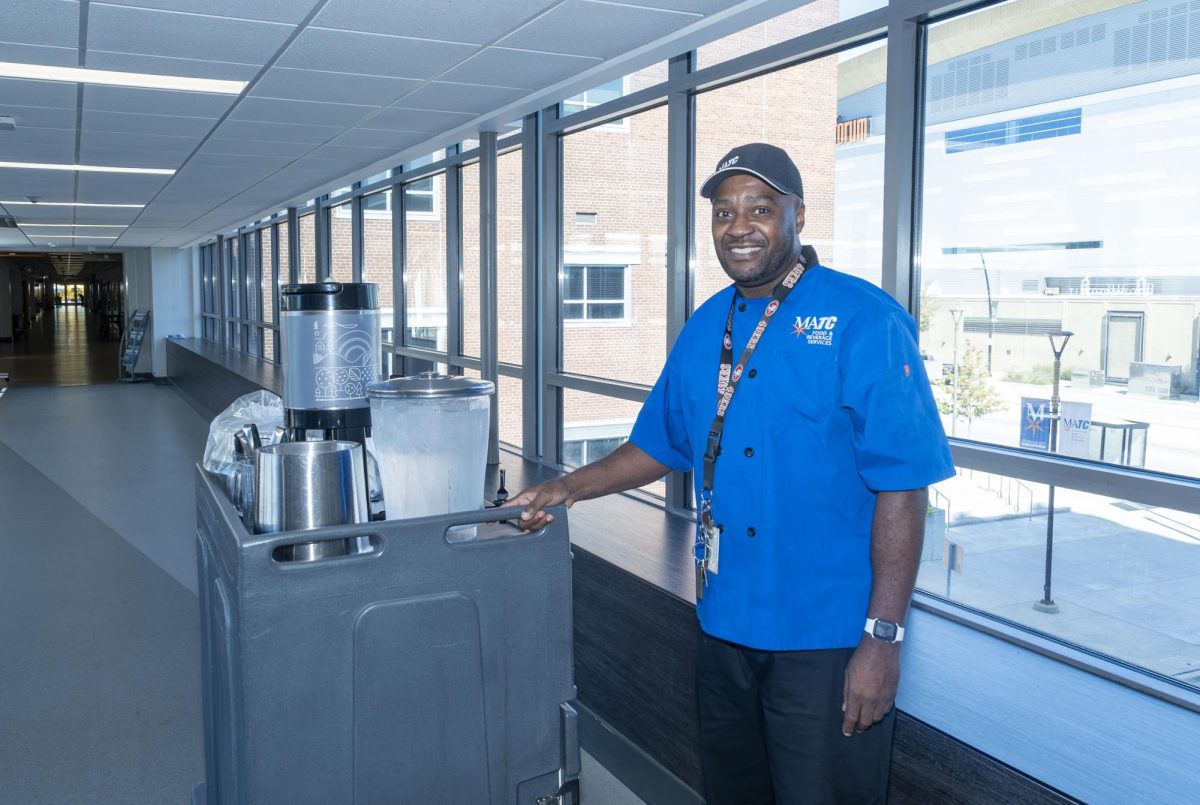 Culinary Assistant, Robert Anderson stops and smiles while taking a catering order to the H Building at the Downtown Campus. 