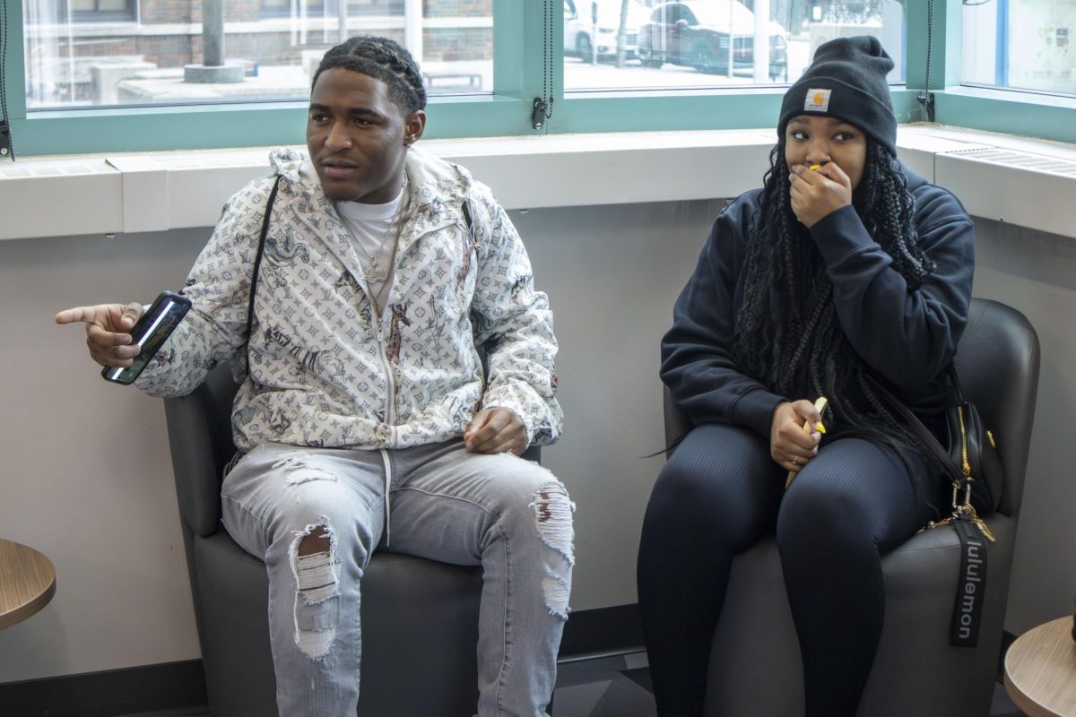 Two students sitting outside the CareerHub, on the first floor of the S Building at the Downtown Milwaukee Campus, demonstrate how they’d initially respond to an Active Shooter Drill. 