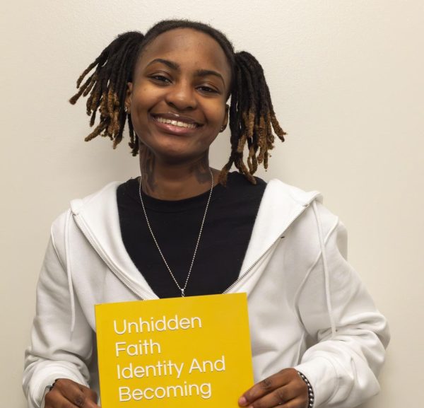 Marianna (Mari) Darrington is a freshman pursuing an associate degree in music occupation. She poses with the book she wrote Unhidden Faith Identity And Becoming Me.
