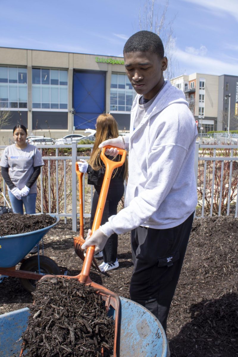 A mentee loads a wheel barrel during the Campus Cleanup event, April 20, 2026