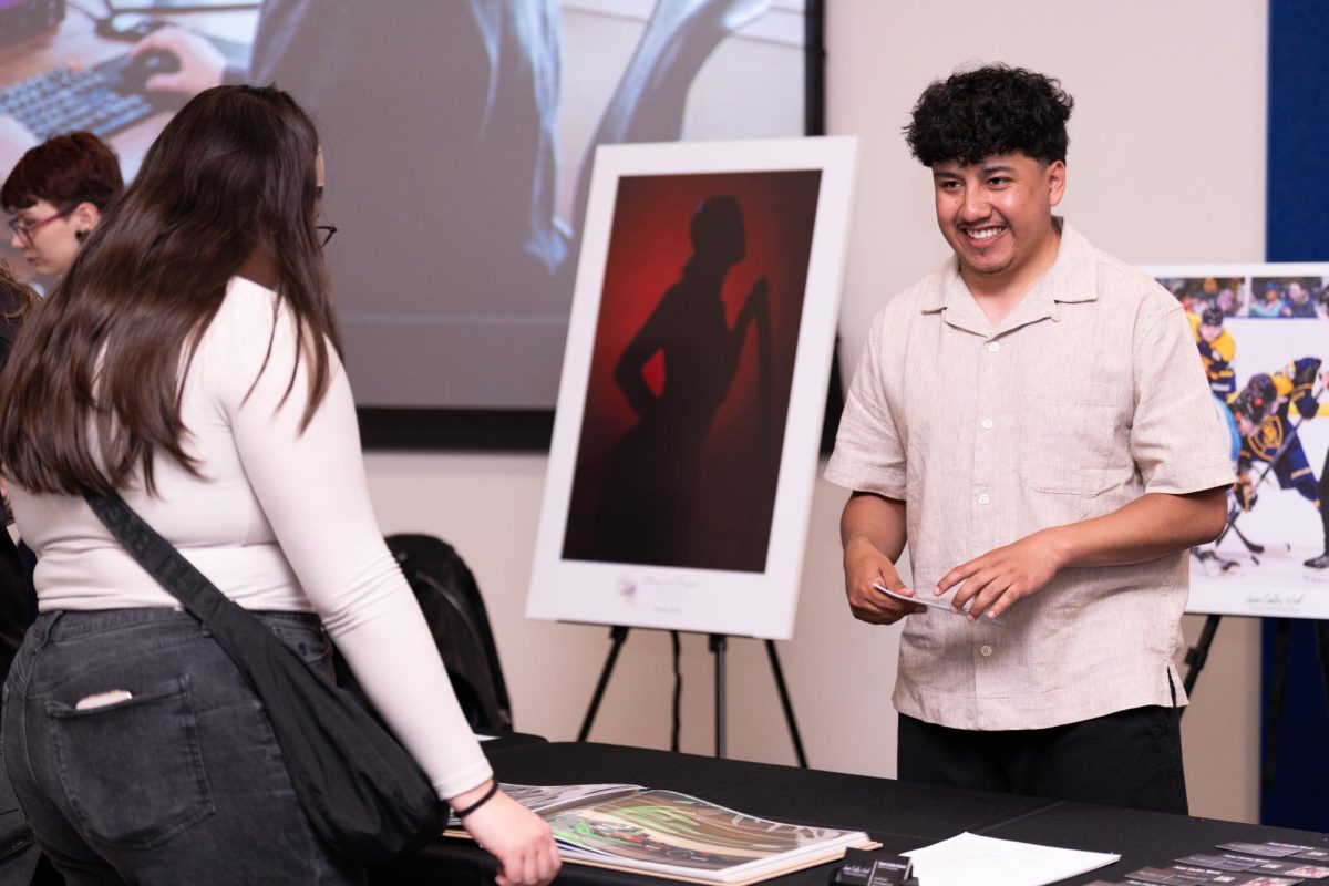 Photography graduate Juan Carlos "JC" Wood shares a laugh with current photography student Emma Guzman